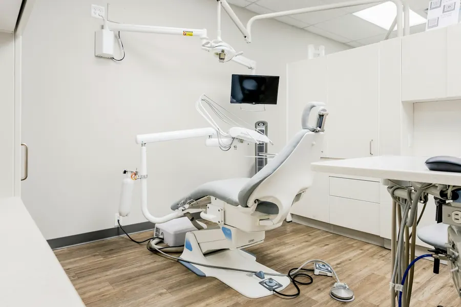 Jasny gabinet stomatologiczny z fotelem, lampą i monitorem
